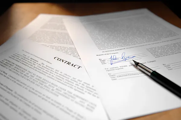 A fountain pen resting on a freshly signed contract