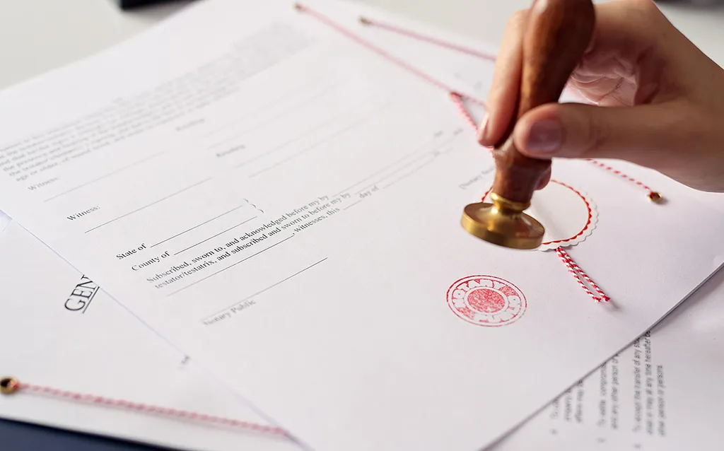 A notary's hand pressing a brass seal onto a signed legal document