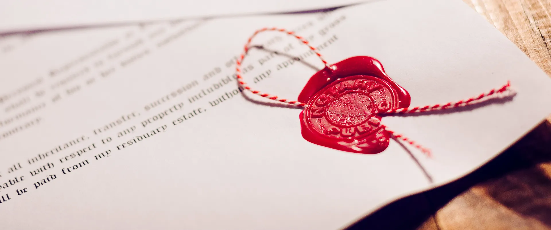 A red wax notary seal tied with red and white string on a legal document